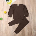 Brown sweatshirt and pants set on a wooden surface with decorative elements.