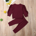 Burgundy outfit with ruffled sleeves on a wooden surface