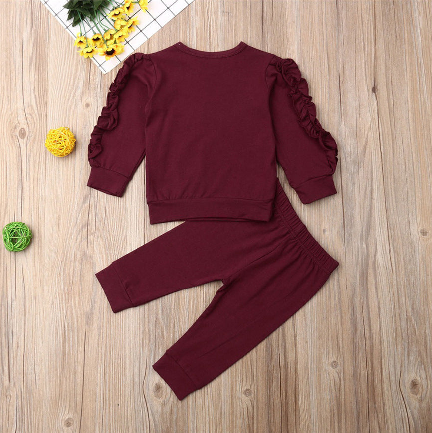 Burgundy outfit with ruffled sleeves on a wooden surface