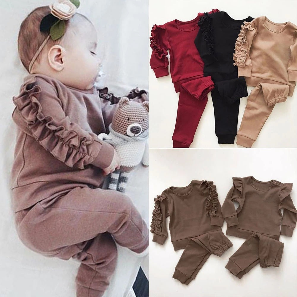 Baby in a brown ruffled outfit with matching set displayed on a white background