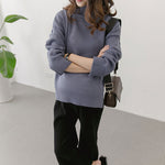 Person wearing a blue sweater and black pants with a white background
