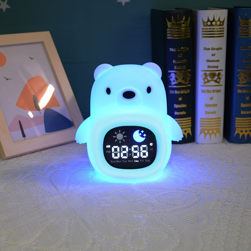 Colorful bear-shaped alarm clock on a surface with books and a framed picture in the background.