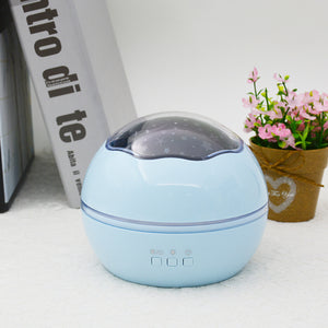 Blue spherical humidifier on a white surface with a plant and book in the background