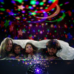 Family under a blanket with colorful star projector on ceiling