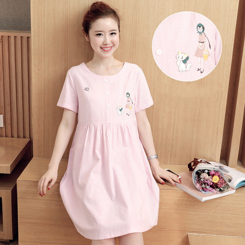 Woman wearing a pink dress with cartoon character design, standing in a room with wooden paneling.