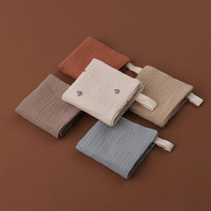 Set of four folded ribbed towels in brown, beige, and blue on a brown background