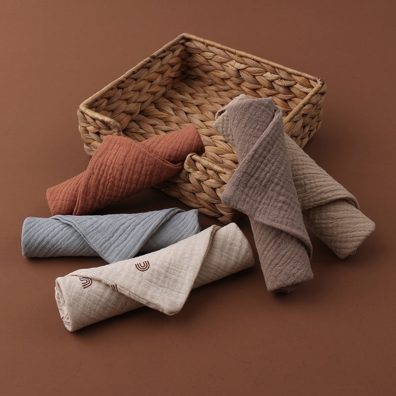 Rolled-up towels in various colors on a woven basket against a brown background
