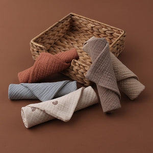 Rolled-up towels in various colors on a woven basket against a brown background