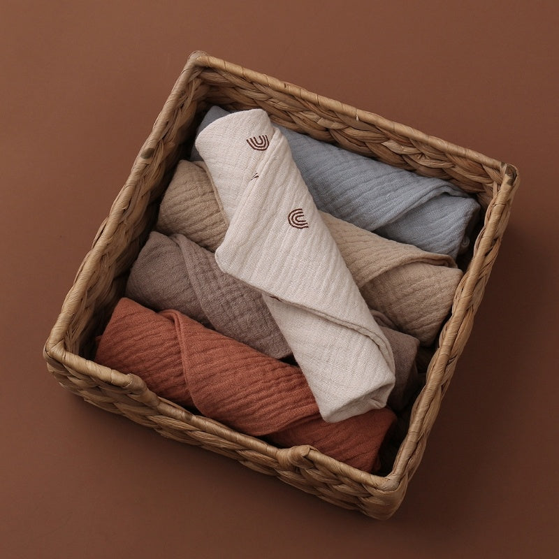 Woven basket with folded baby clothes on a brown background
