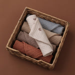 Woven basket with folded baby clothes on a brown background