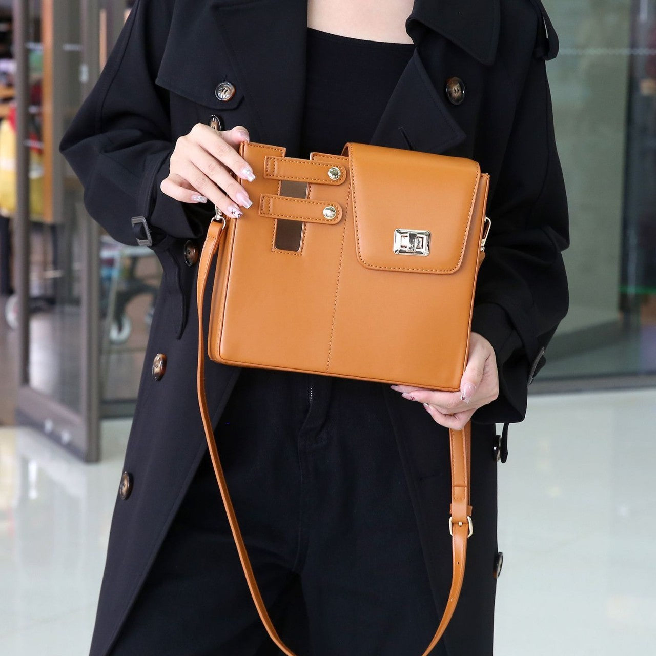 Person holding a brown handbag in an indoor setting
