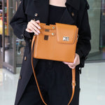 Person holding a brown handbag in an indoor setting