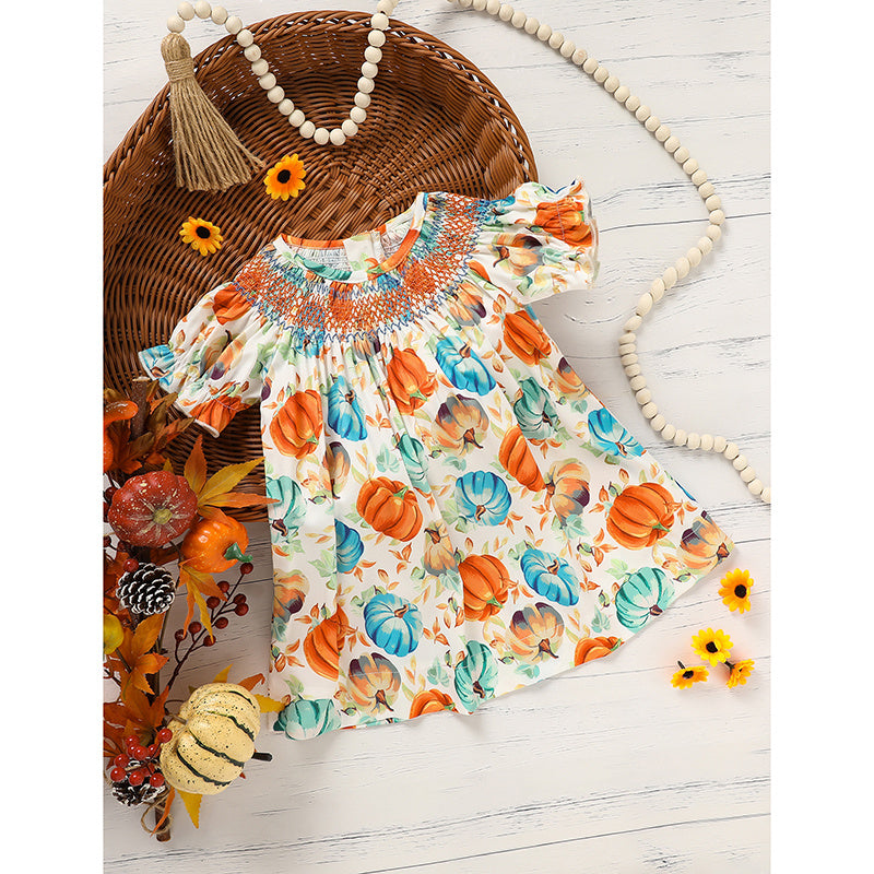 Colorful dress with pumpkin pattern on a wooden surface with decorative elements.