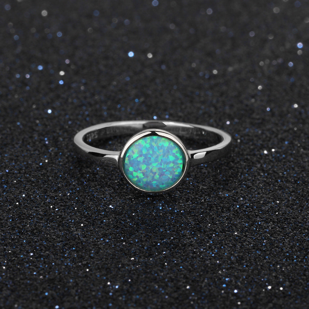 Silver ring with a green opal stone on a black textured background