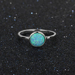 Silver ring with a green opal stone on a black textured background