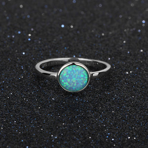 Silver ring with a green opal stone on a black textured background