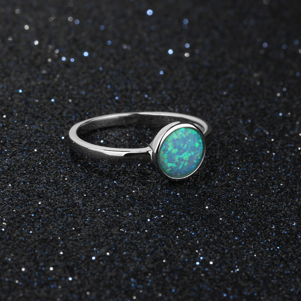 Silver ring with a green opal stone on a black glittery background