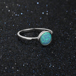 Silver ring with a green opal stone on a black glittery background