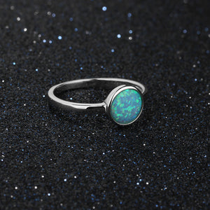 Silver ring with a green opal stone on a black glittery background
