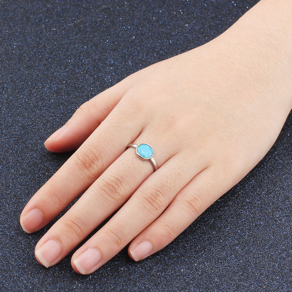 Hand wearing a silver ring with a blue gemstone on a dark textured background