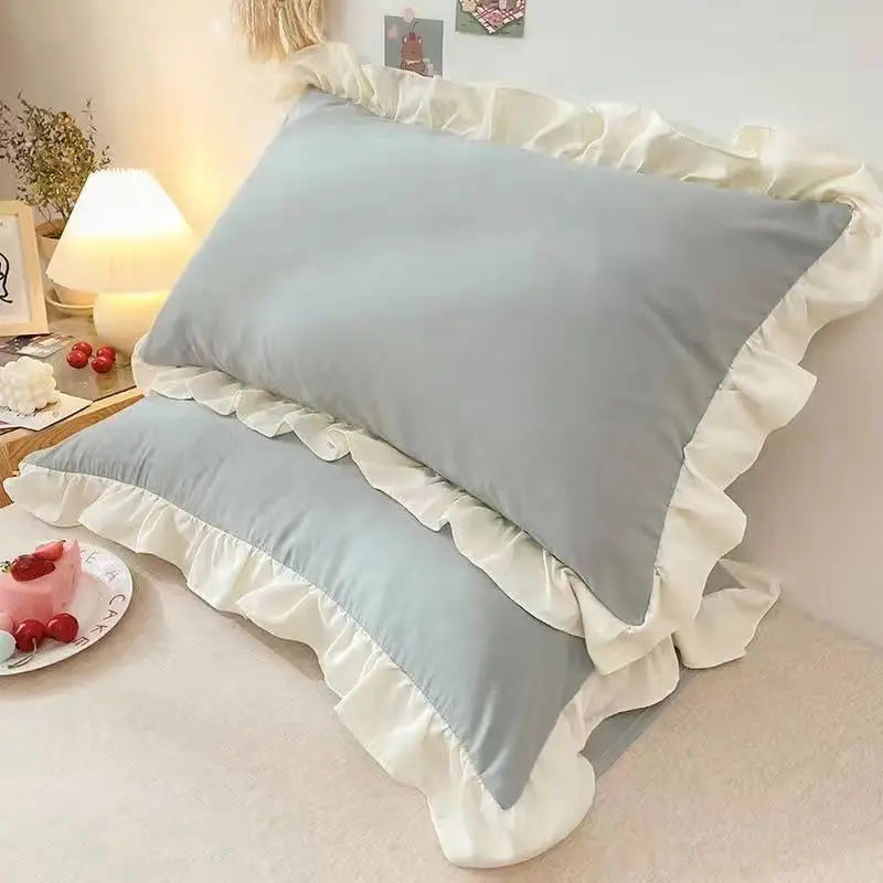 Gray pillows with ruffled edges on a bed in a bedroom setting.