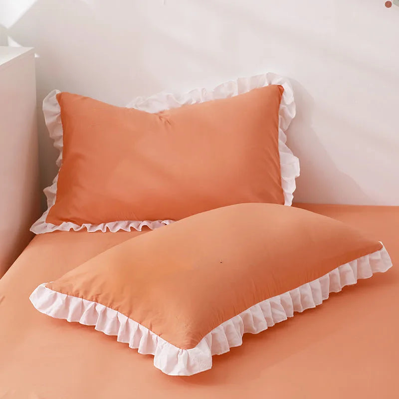 Orange pillows with ruffled edges on a bed in a bedroom setting.