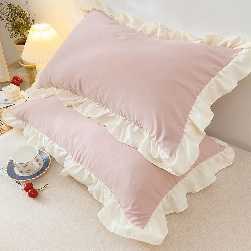 Pink pillows with ruffled edges on a bed in a bedroom setting.
