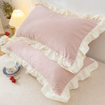 Pink pillows with ruffled edges on a bed in a bedroom setting.