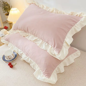 Pink pillows with ruffled edges on a bed in a bedroom setting.