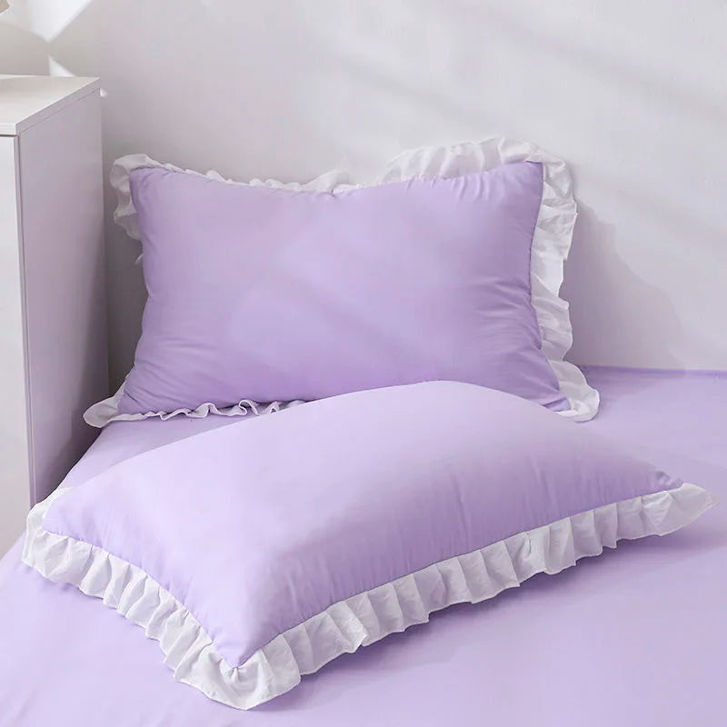 Purple pillows with ruffled edges on a bed in a bedroom setting.