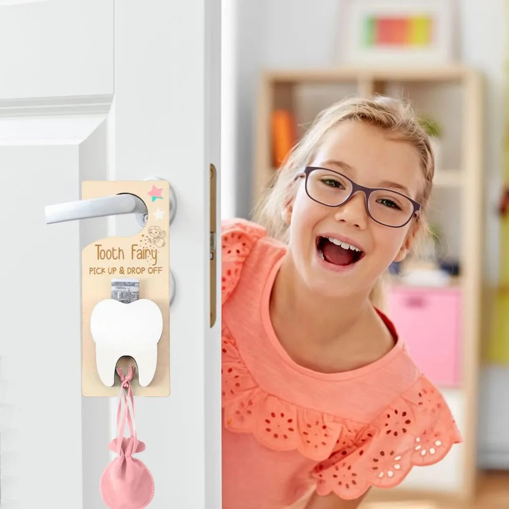 Girl with glasses looking at a 'Tooth Fairy' door hanger on a white door.