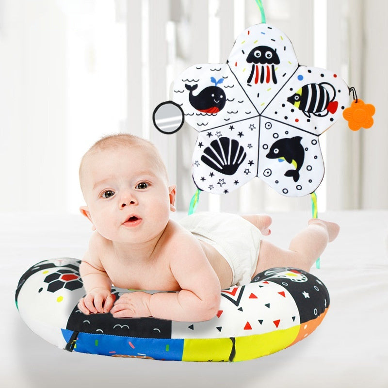 Baby lying on a colorful ring with a educational toy hanging above