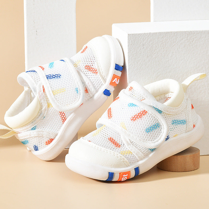 White children's sandals with colorful accents on a beige surface
