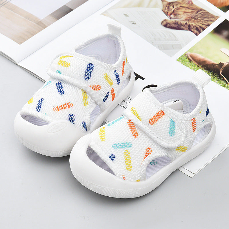 White children's sandals with colorful patterns on a light gray surface.