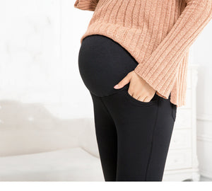 Person wearing black leggings with a beige sweater on a white background